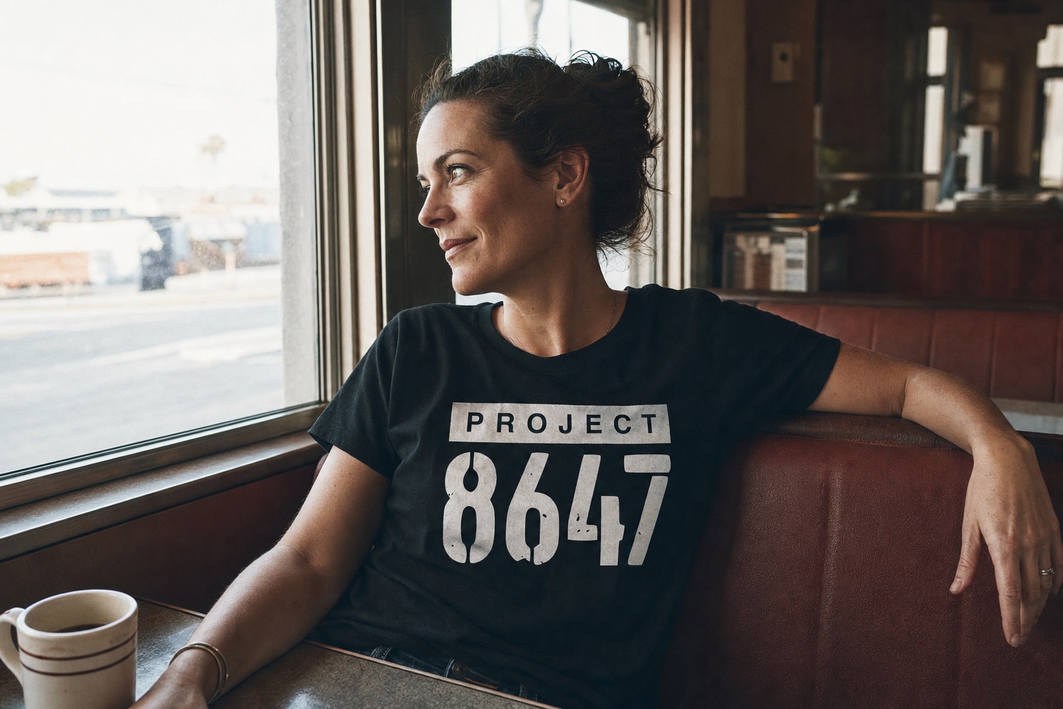 Woman wearing a black Project 8647 T-shirt in a neighborhood diner